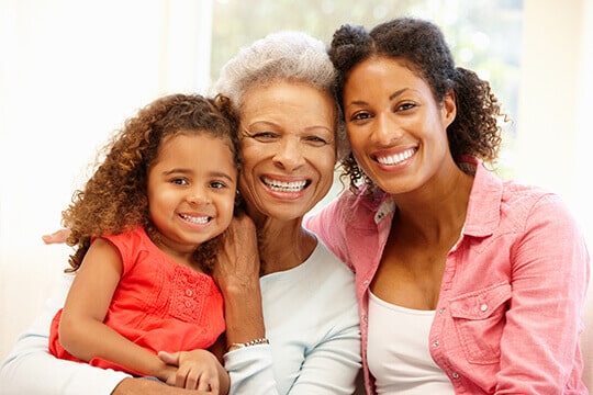 Grandmother smiling with daughter and granddaughter in embrace