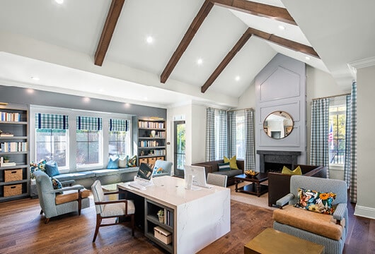 Longleaf library windows centered by bookcases with desk in center, chairs throughout room and couches by fireplace