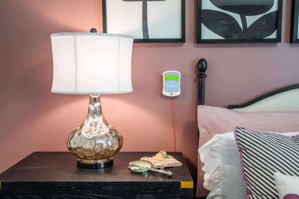 White and glass lamp, magnifying glass and letters sitting on black nightstand next to bed in Longleaf assisted living model apartment