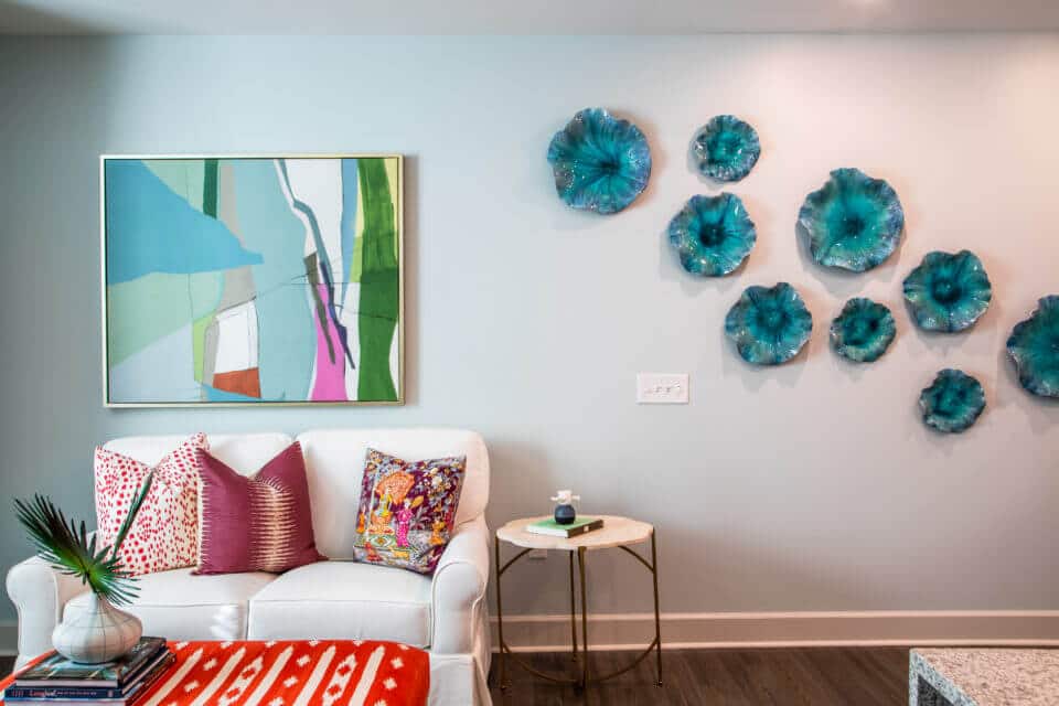 White living room sofa with colorful pillows, ottoman and wall art in Longleaf assisted living model apartment