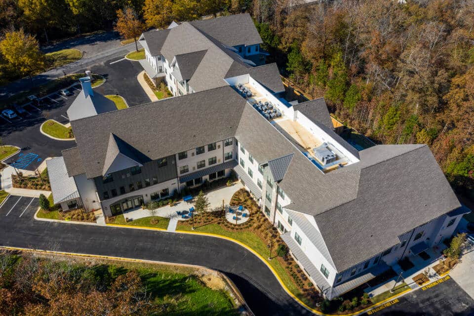 Aerial view of back of Longleaf community with blue patio furniture in view and treed area to right