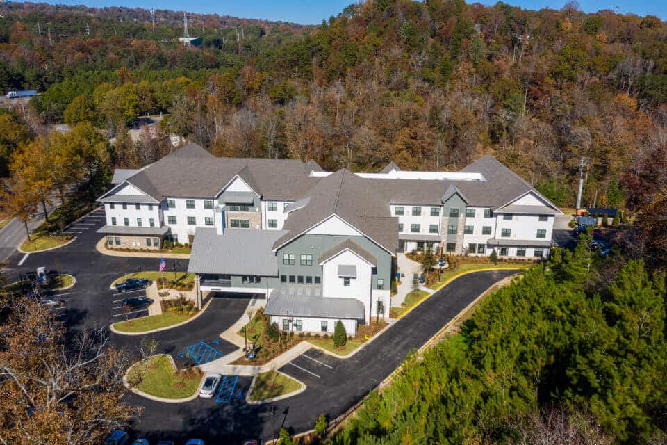 Aerial view of side of Longleaf community showing side parking lot and treed area behind community