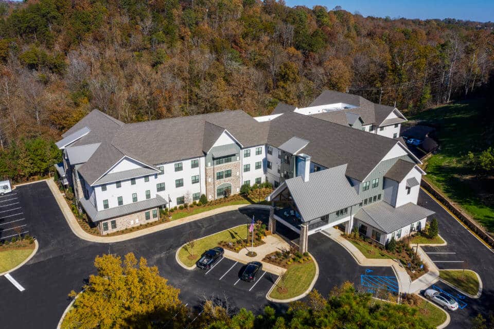 Aerial view of front of Longleaf community showing parking lot in front and treed area behind community