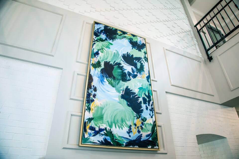Blue, green and yellow framed art on white wall in Longleaf foyer