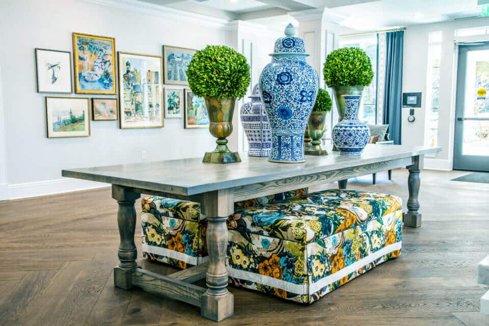 Long table with blue and white vases, greenery in pots on top and floral benches below in Longleaf foyer