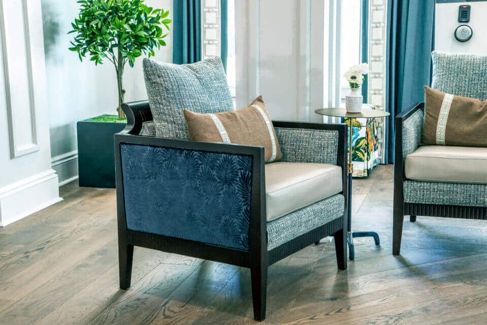 Two blue and beige chairs with table flowers in vase in Longleaf common space