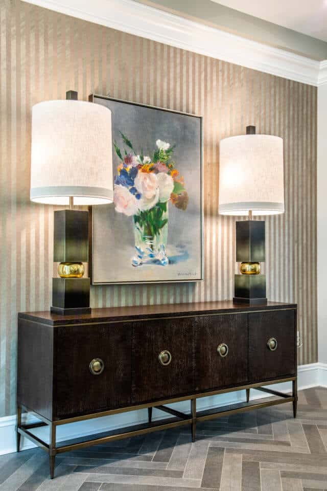 Brown table under framed floral art centered by two lamps with white shades in Longleaf common space