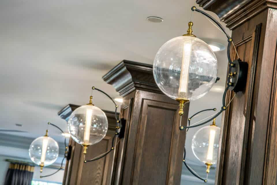 Glass globe light fixtures with gold and black mounting on wooden columns in Longleaf common space