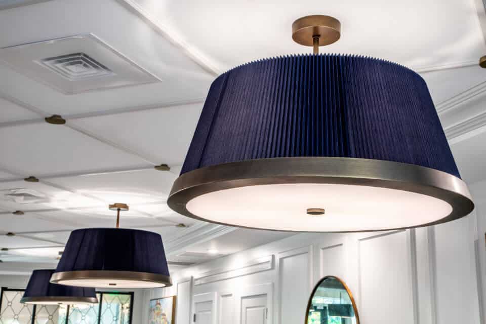 Blue lamp shades on light fixtures with bronze fixtures on white ceiling in Longleaf common space