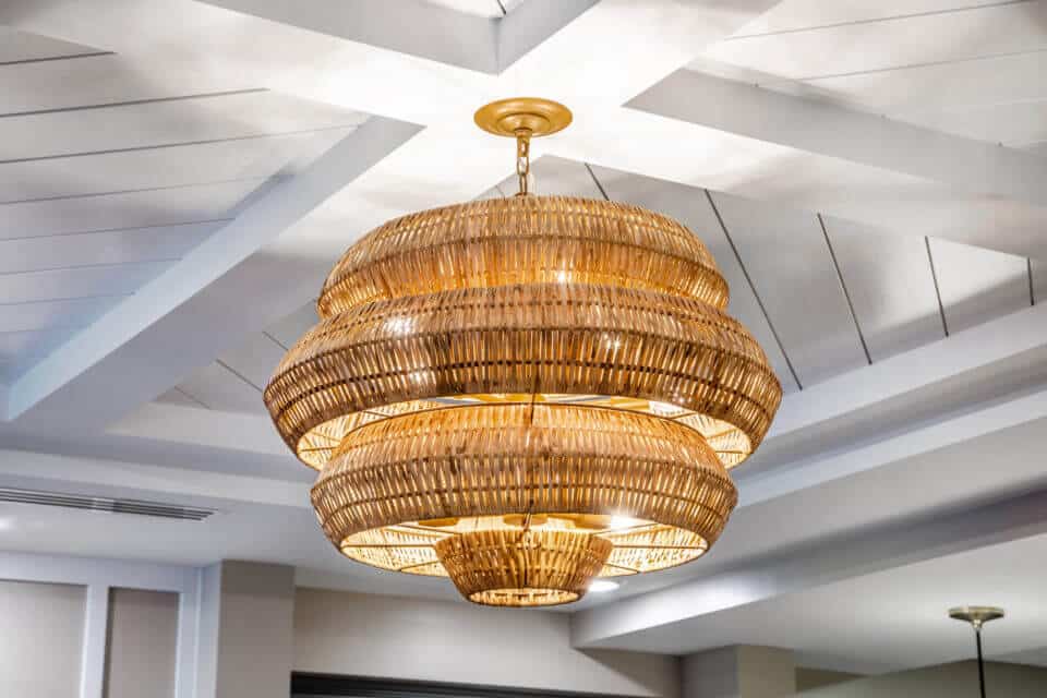 Basket weave like light fixture hanging from white wooden ceiling in Longleaf common space