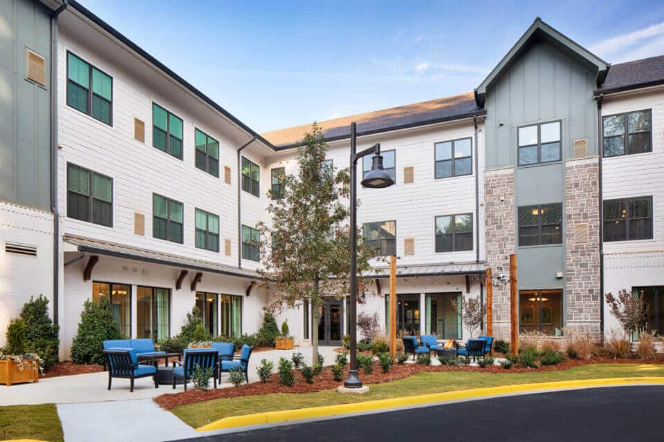 Longleaf courtyard patio with blue chairs and firepits burning, lights hanging above