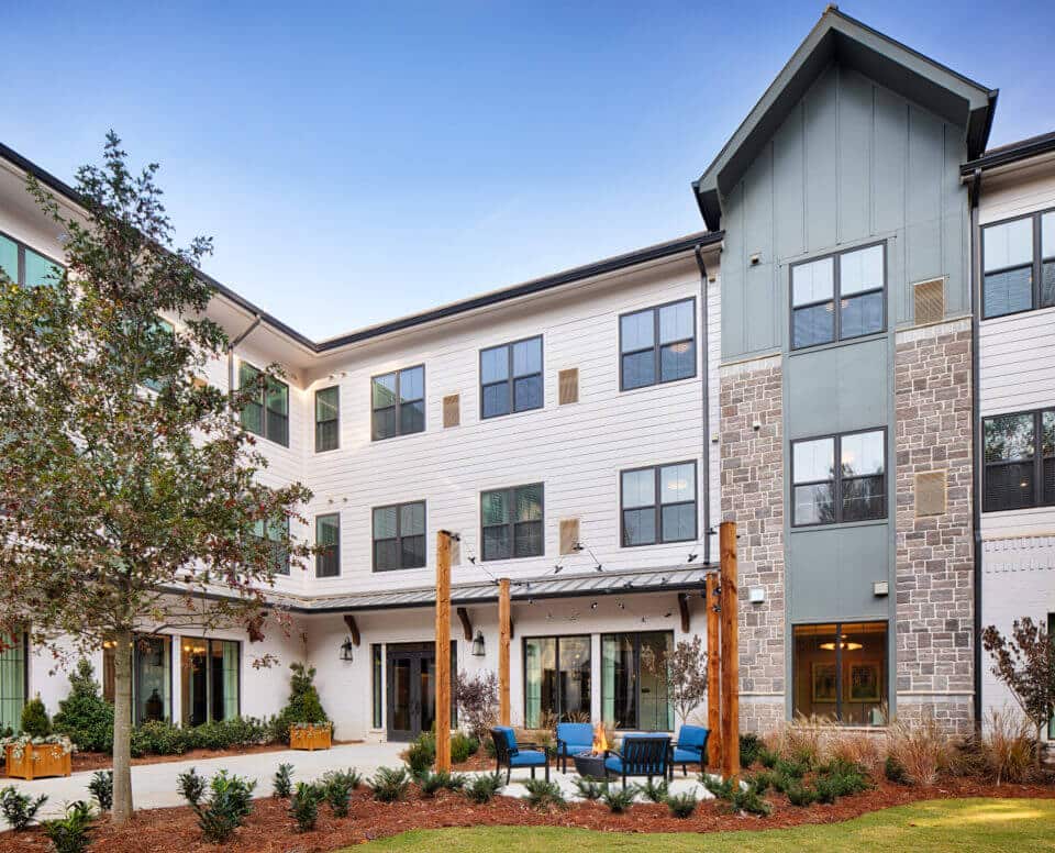 Longleaf courtyard patio with blue chairs and firepits burning, lights hanging above