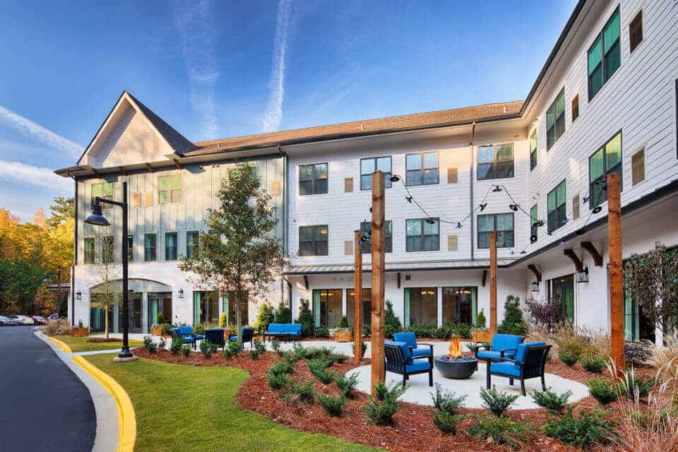 Longleaf courtyard patio with blue chairs and firepits burning, lights hanging above