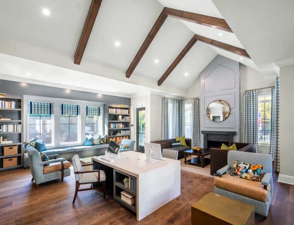 Longleaf library windows centered by bookcases with desk in center, chairs throughout room and couches by fireplace