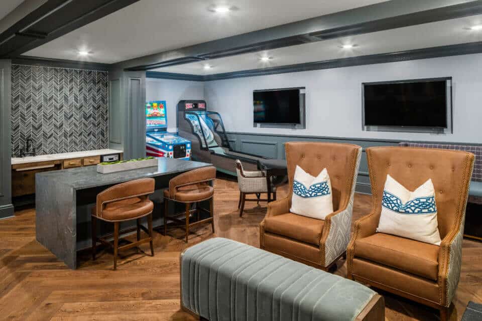 Longleaf lounge bard and stools at left, arcade games to right of bar, two brown leather chairs with white and blue pillows at right with light green ottoman