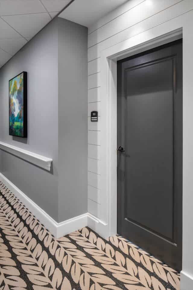 Longleaf hallway with white walls and residents' blue doors at right, gray walls at left