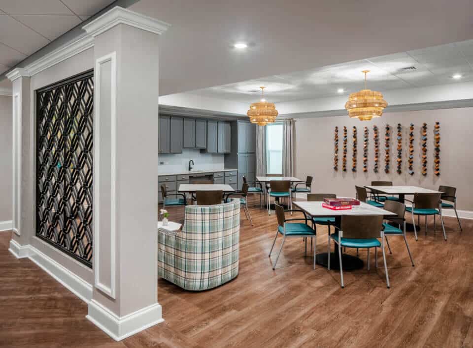 Longleaf common space with decorative wall at left, tables and chairs with hanging cube wall art at right