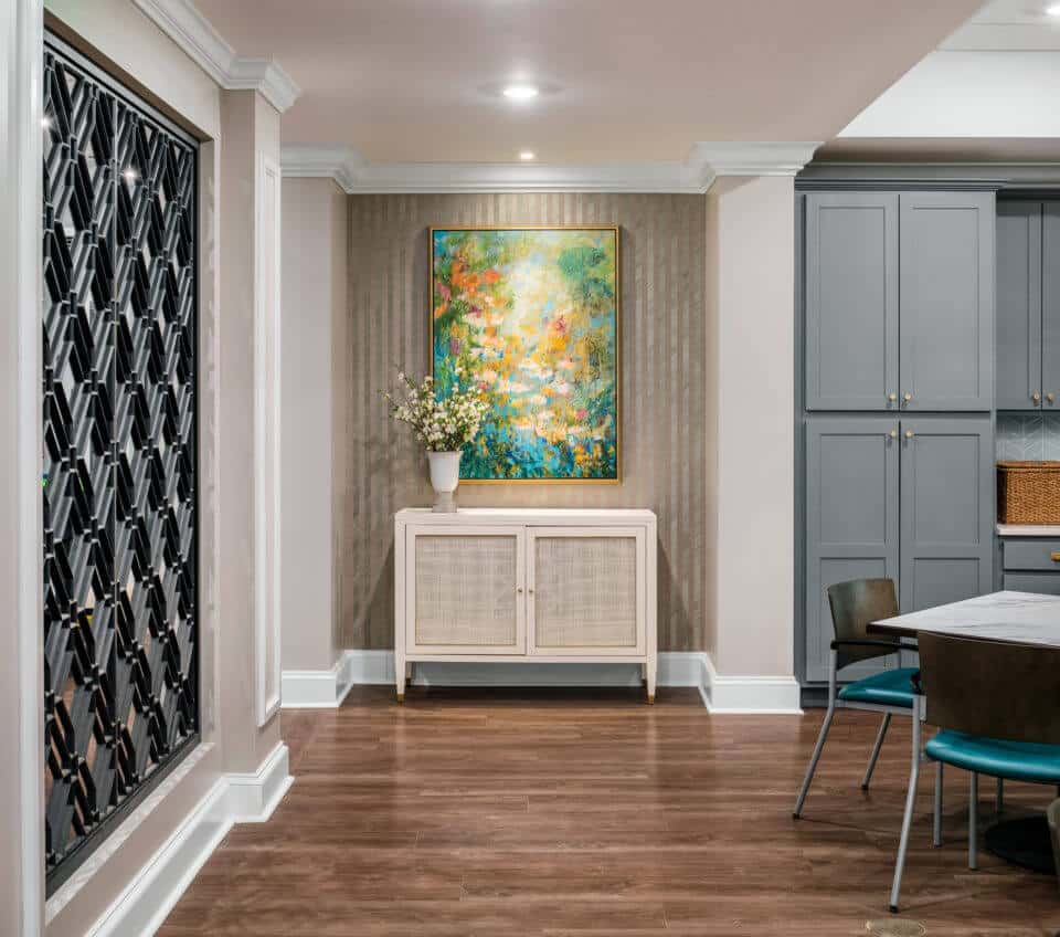 Longleaf common space with decorative wall at left painting, flowers in vase, and table against back wall, chairs with table at right