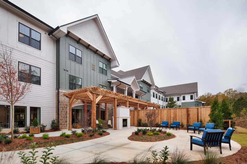 Longleaf patio with blue chairs, outdoor fireplace and wooden pergola and fence