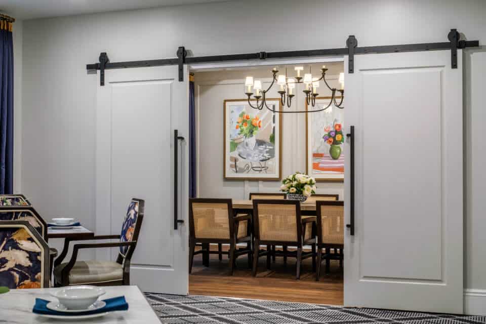 View of Longleaf private dining room with sliding white doors from main dining room with tables and chairs
