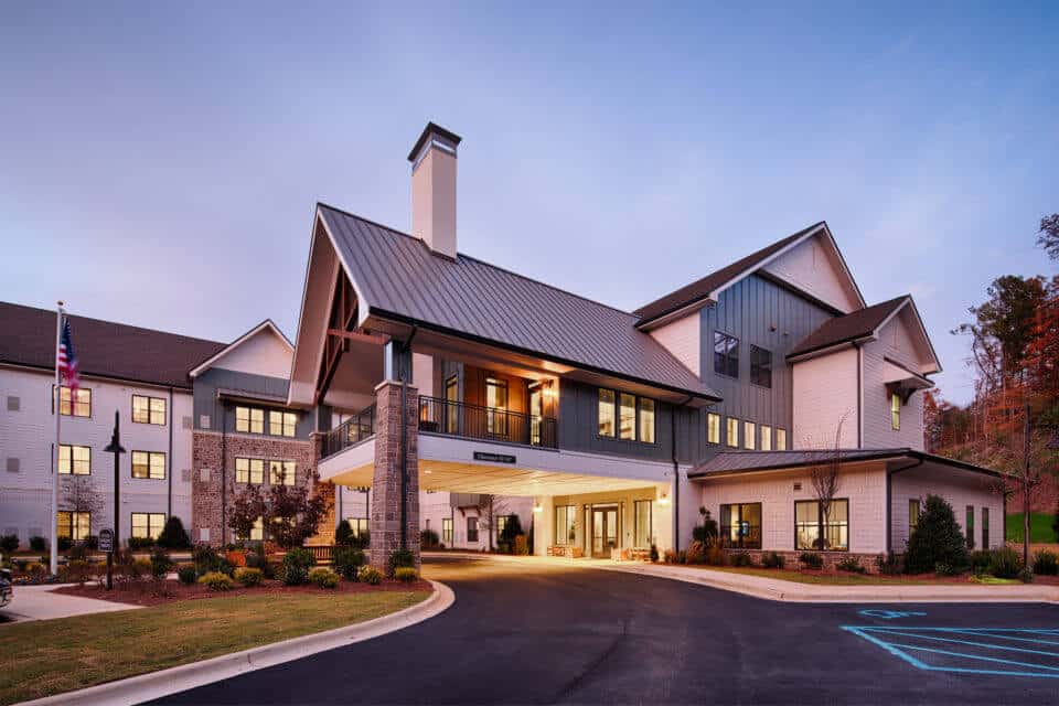 Exterior view of Longleaf Liberty Park entrance with circle drive at dusk with lights on and dark blue skies