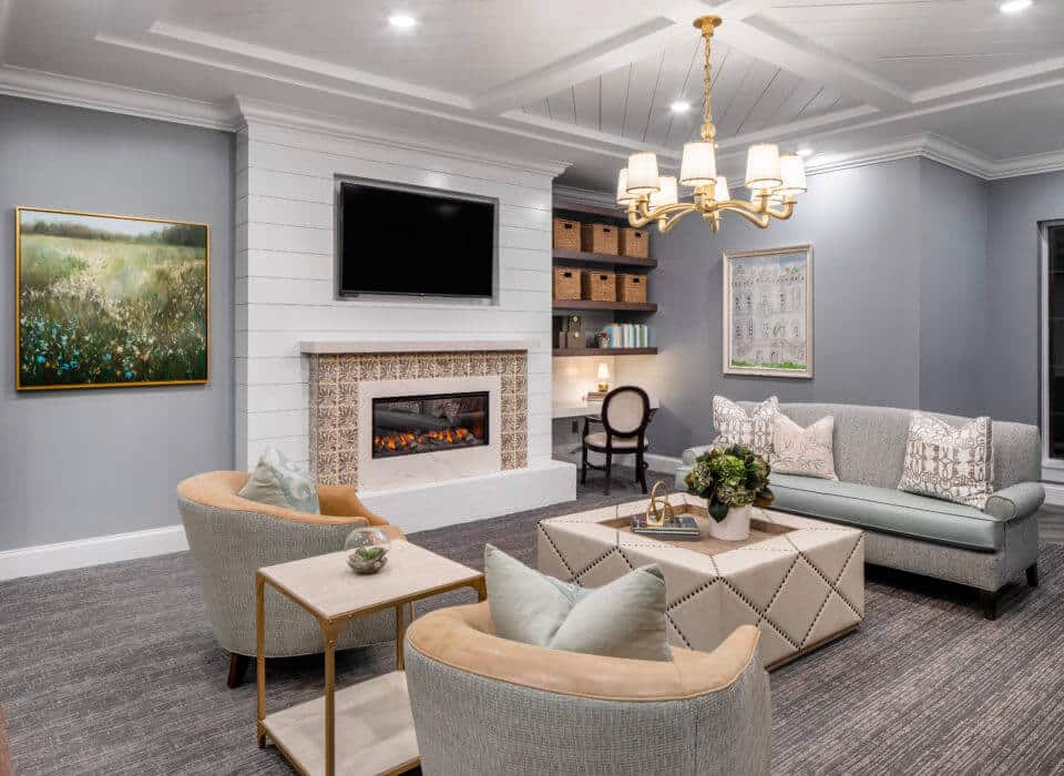 Longleaf common space with TV mounted above fireplace, couches and chairs with ottoman in front