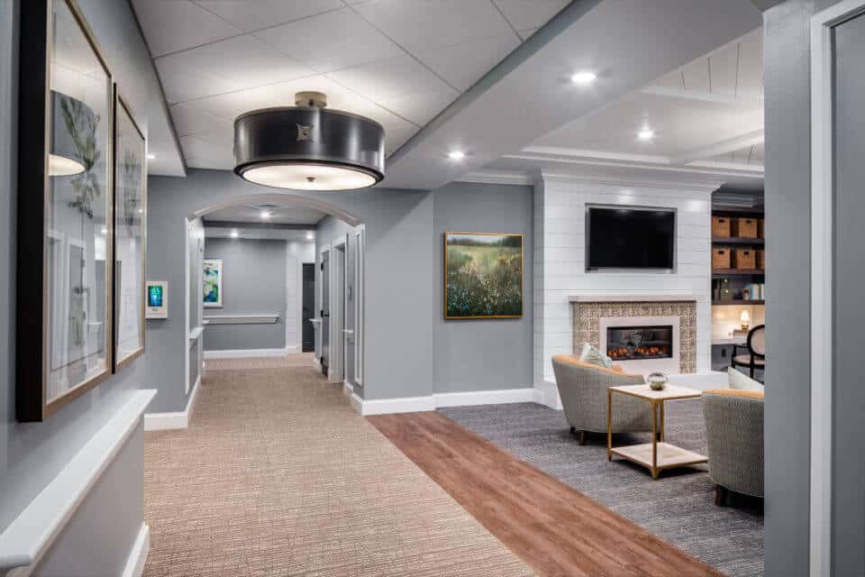 Hallway with view of Longleaf common space with chairs and fireplace at right