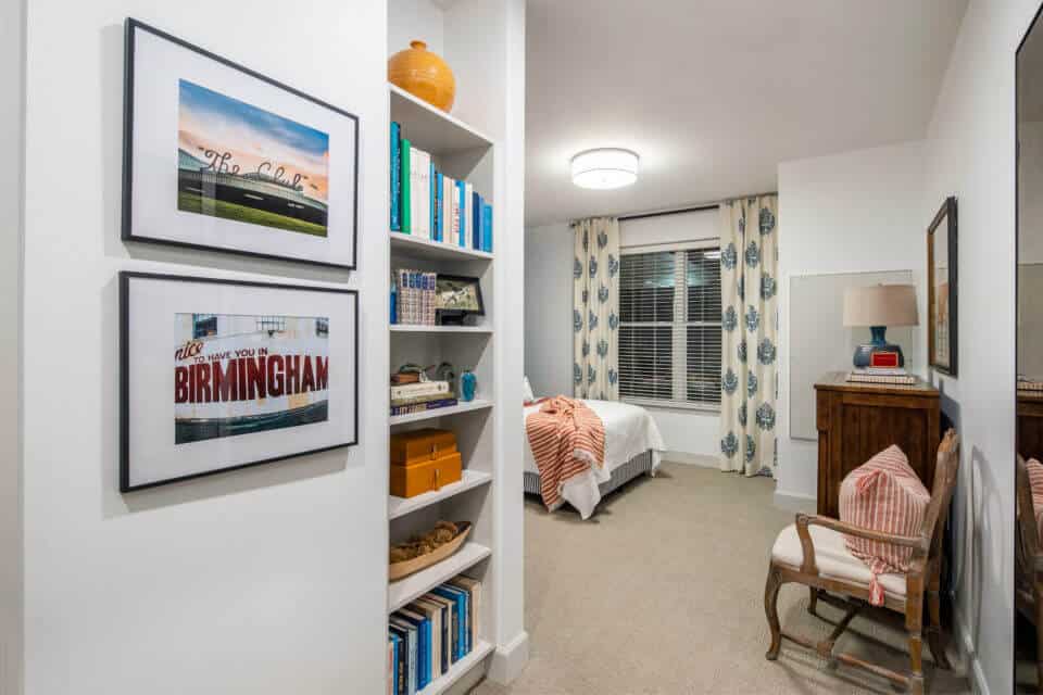 Built in bookshelf, framed art hanging on wall, white bed, chair and dresser in Longleaf memory care model apartment