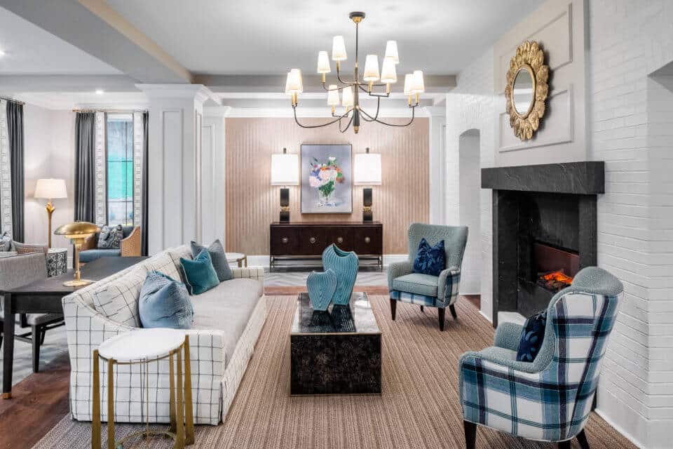White plaid sofa, black ottoman, blue plaid chairs in front of fireplace in Longleaf common area