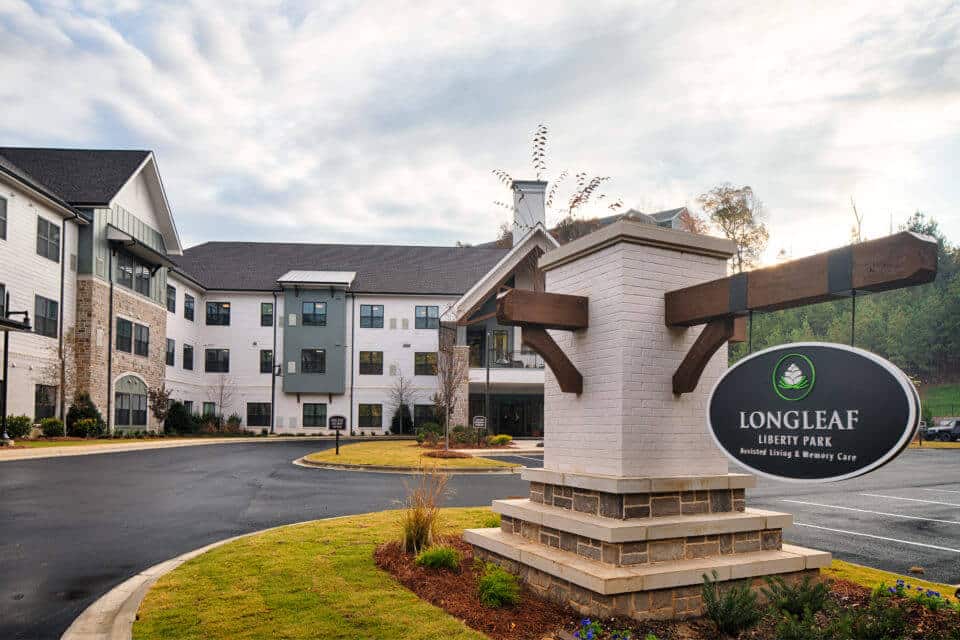 Longleaf Liberty Park front entrance monument sign at daytime with community to left and blue skies with white clouds