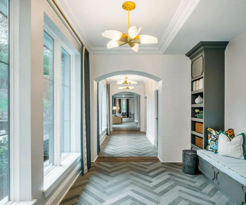 Longleaf common space with arched hallway, windows at left, gray shelves, bench seating, white walls and grey chevron pattern on flooring